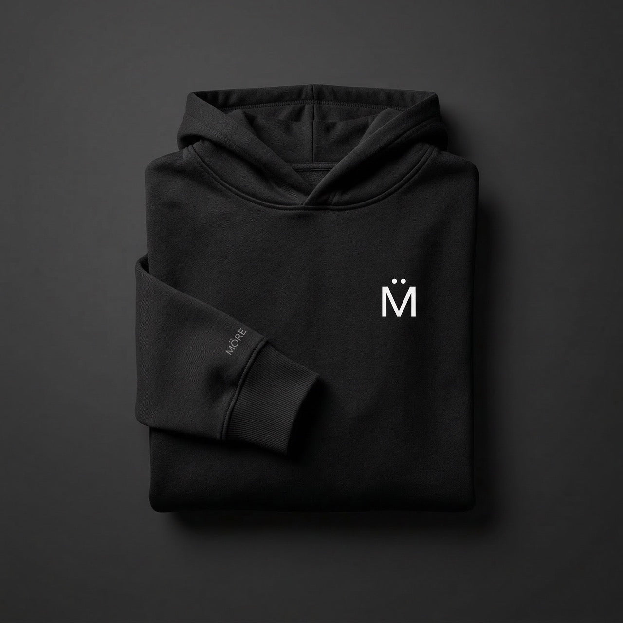 Folded black hoodie with a logo on a dark gray background