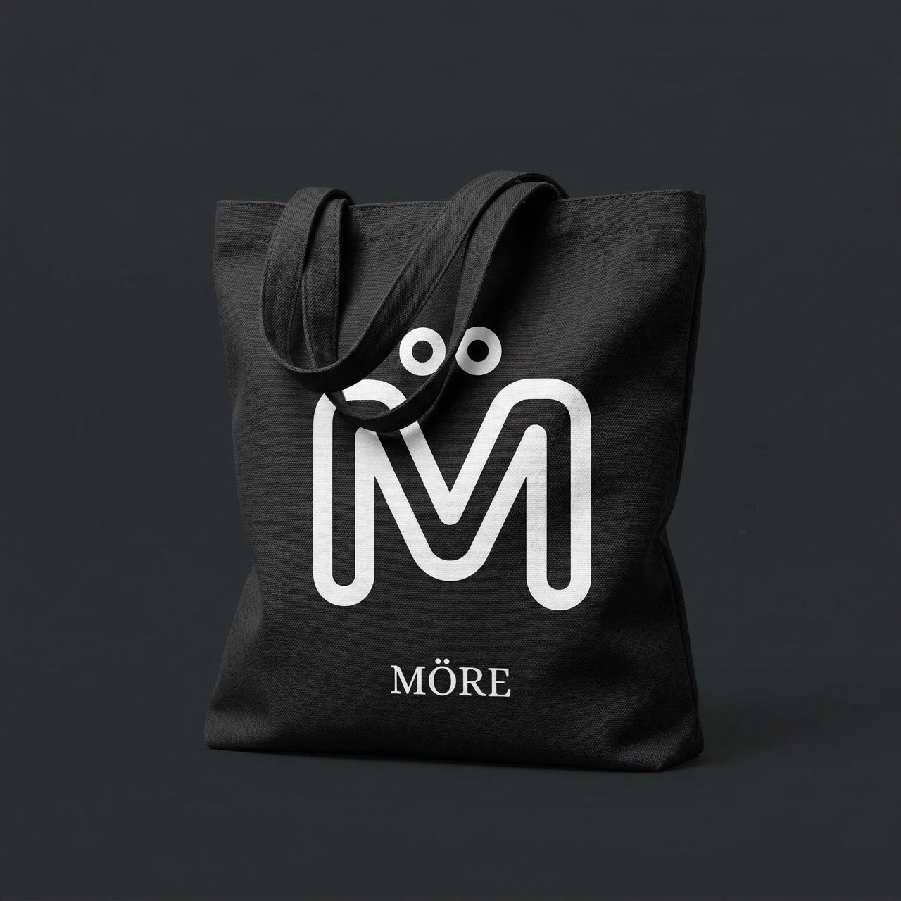 Black tote bag with a white logo and 'Möre' text on a dark background